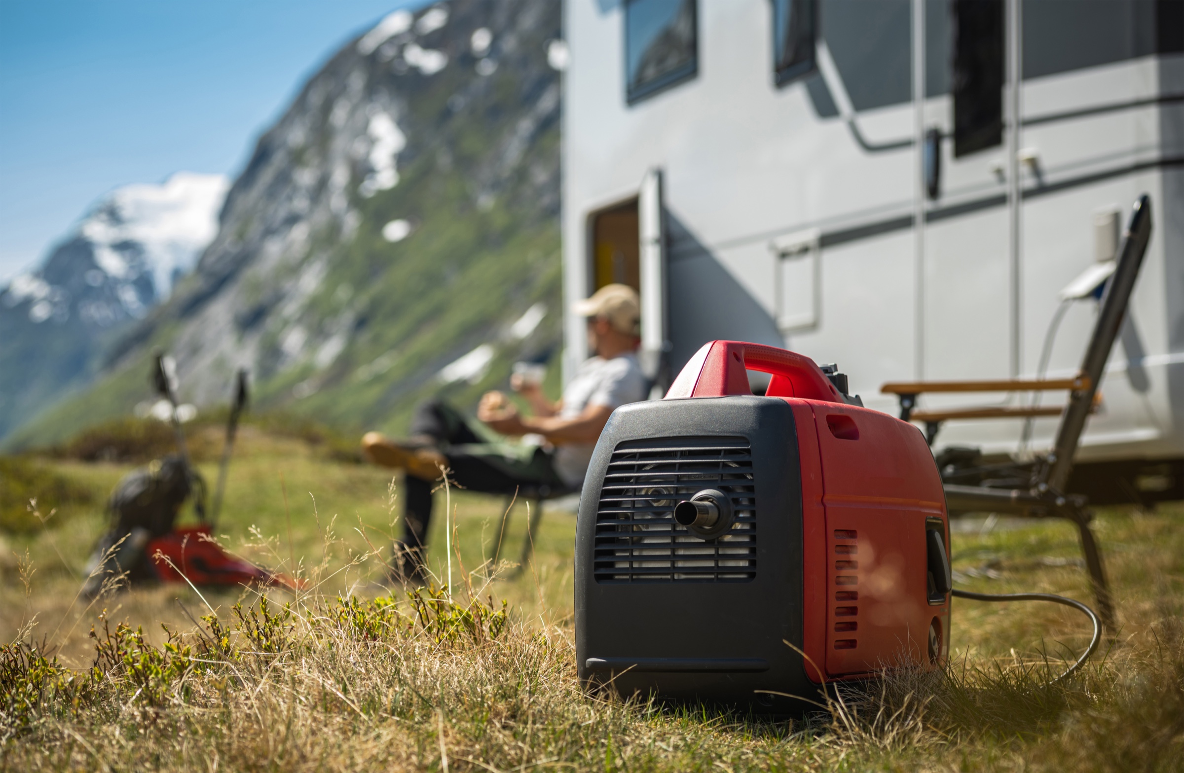 A compact inverter generator positioned outdoors beside a camper