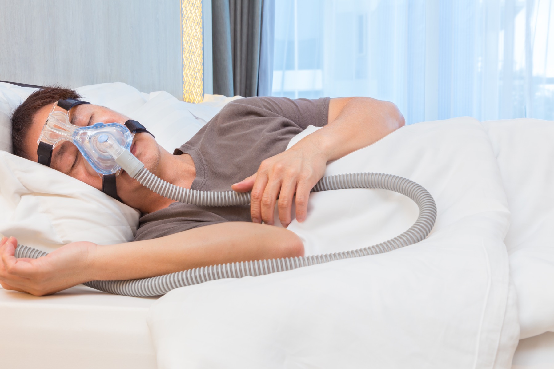 A person sleeping with a CPAP mask and air hose