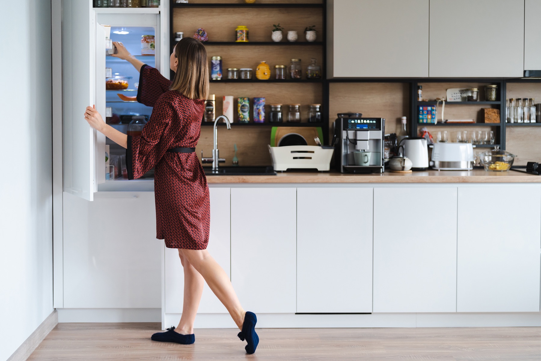 A person opening a refrigerator in a modern home kitchen