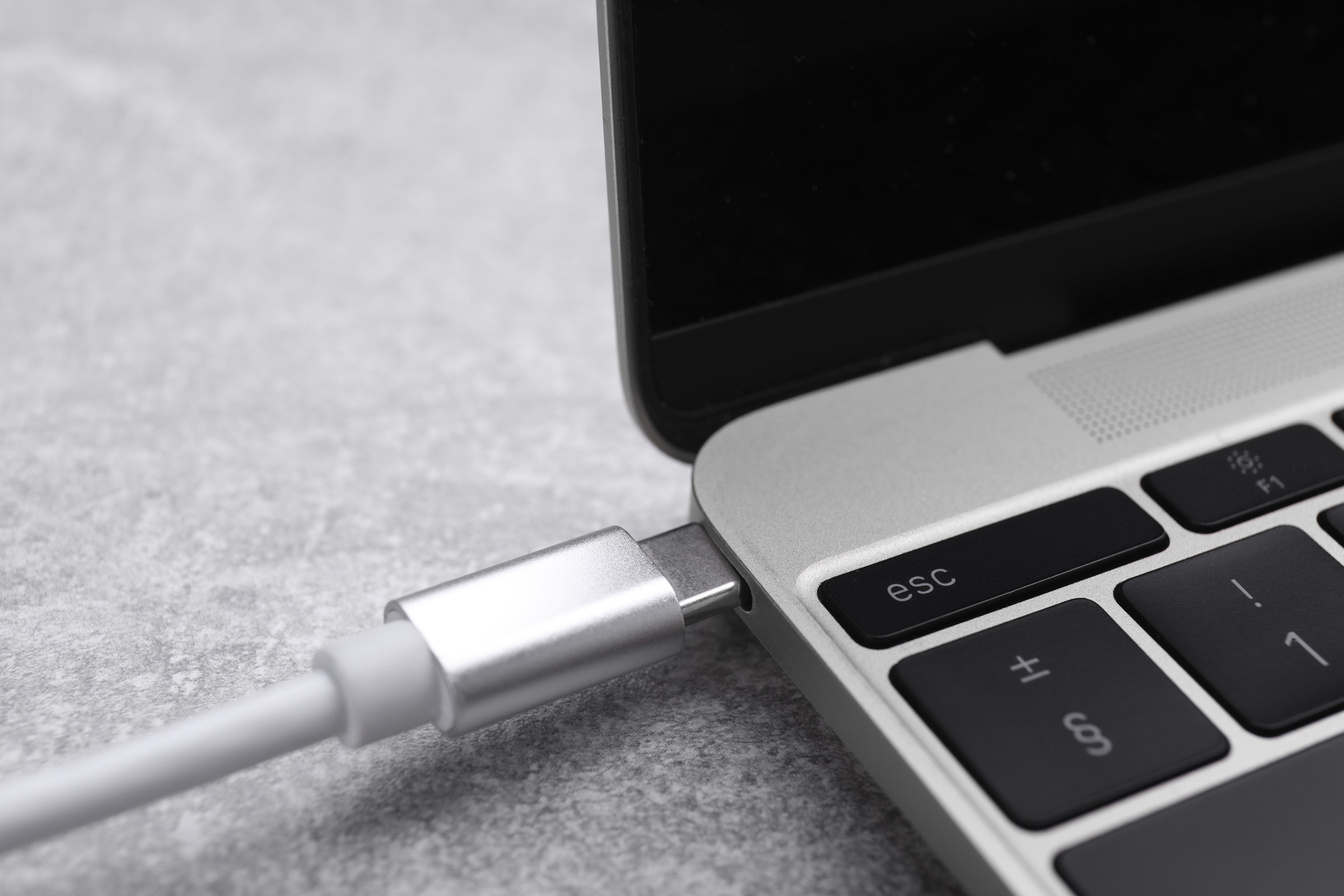 A USB-C cable connected to the charging port of a laptop