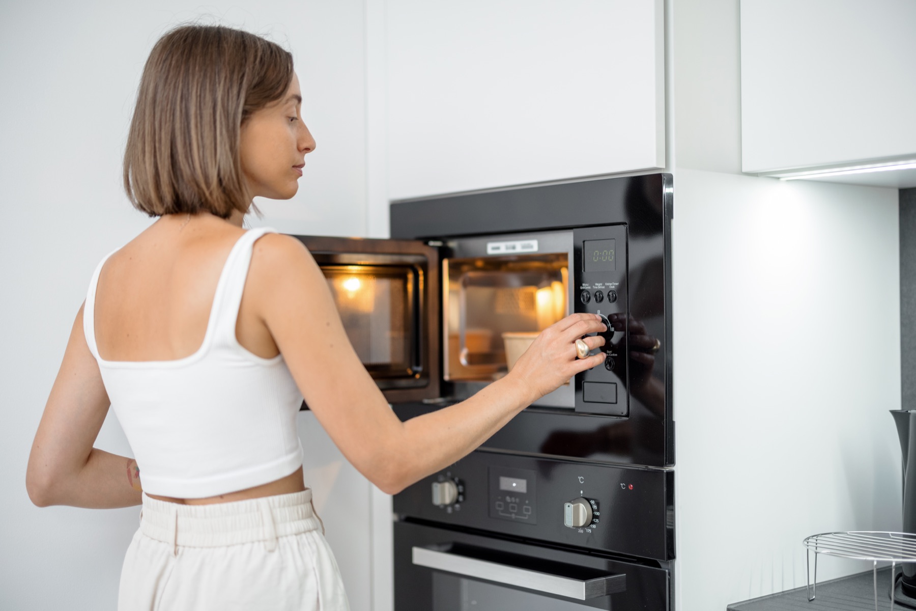 A person operating a built-in microwave in a home kitchen