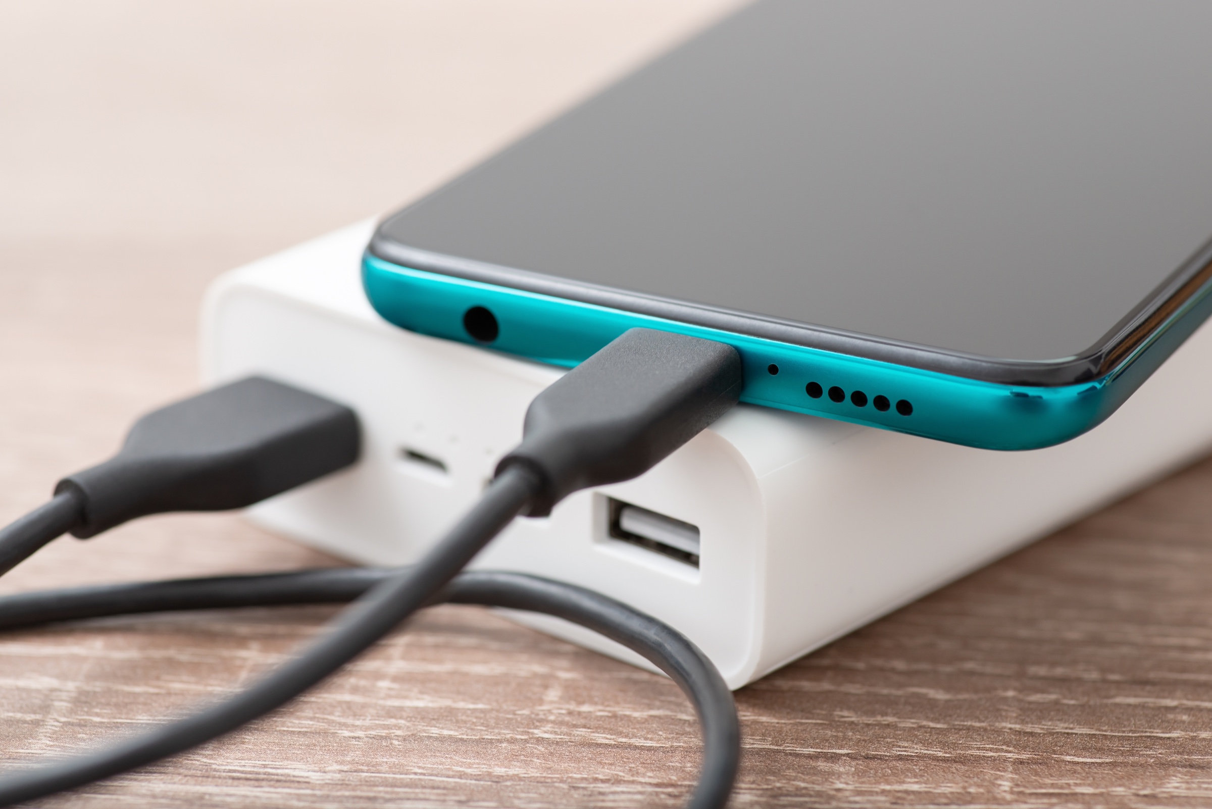 A smartphone charging from a compact power bank over USB-C