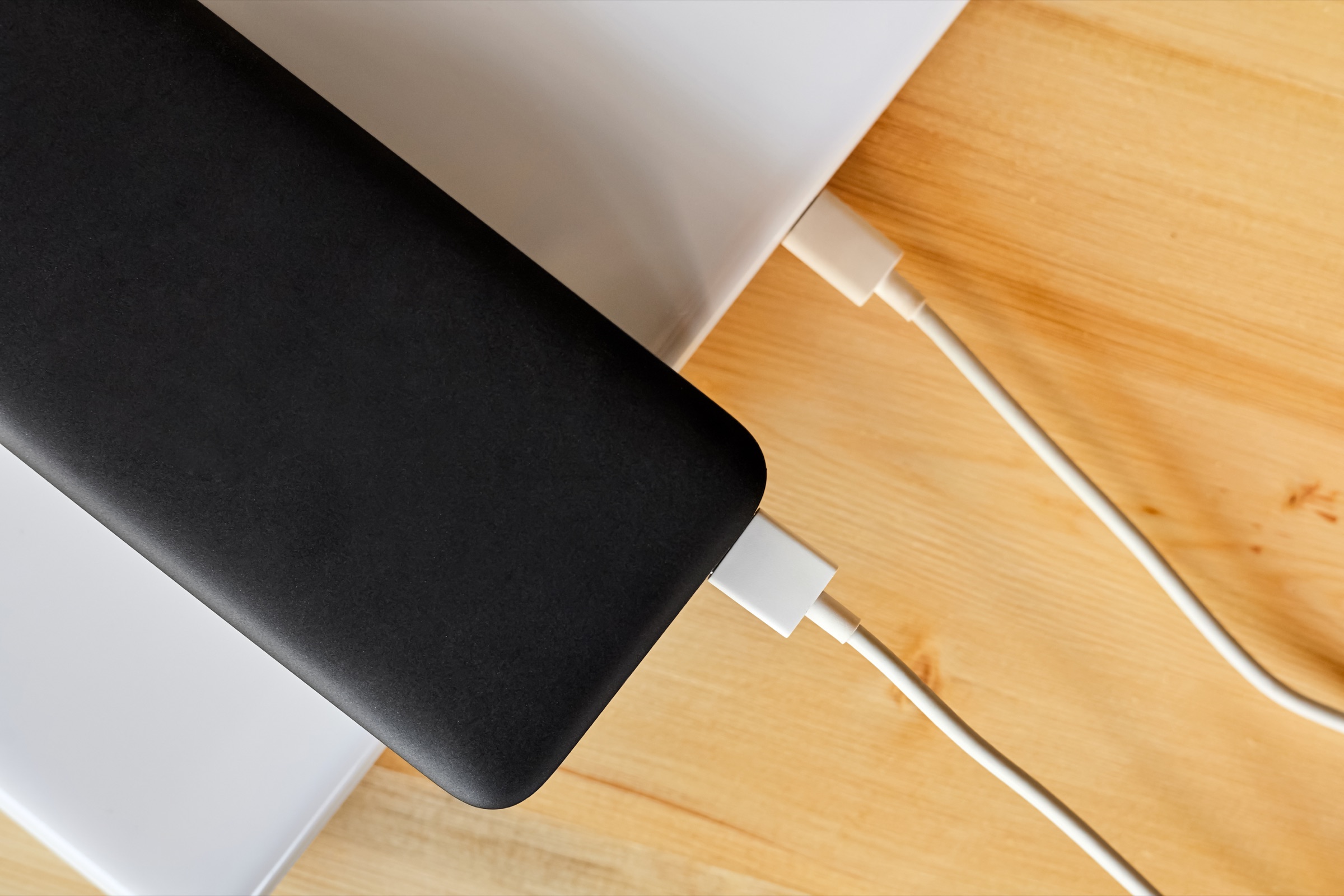 A USB-C power bank connected directly to a laptop