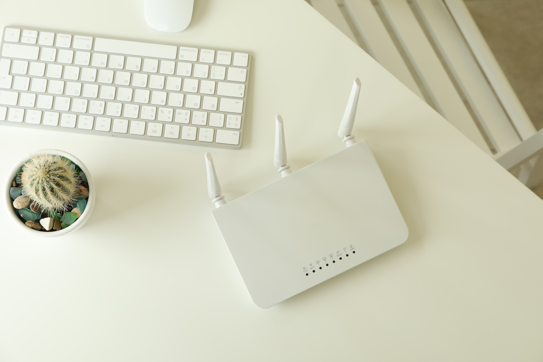 A wireless router beside a keyboard on a home-office desk