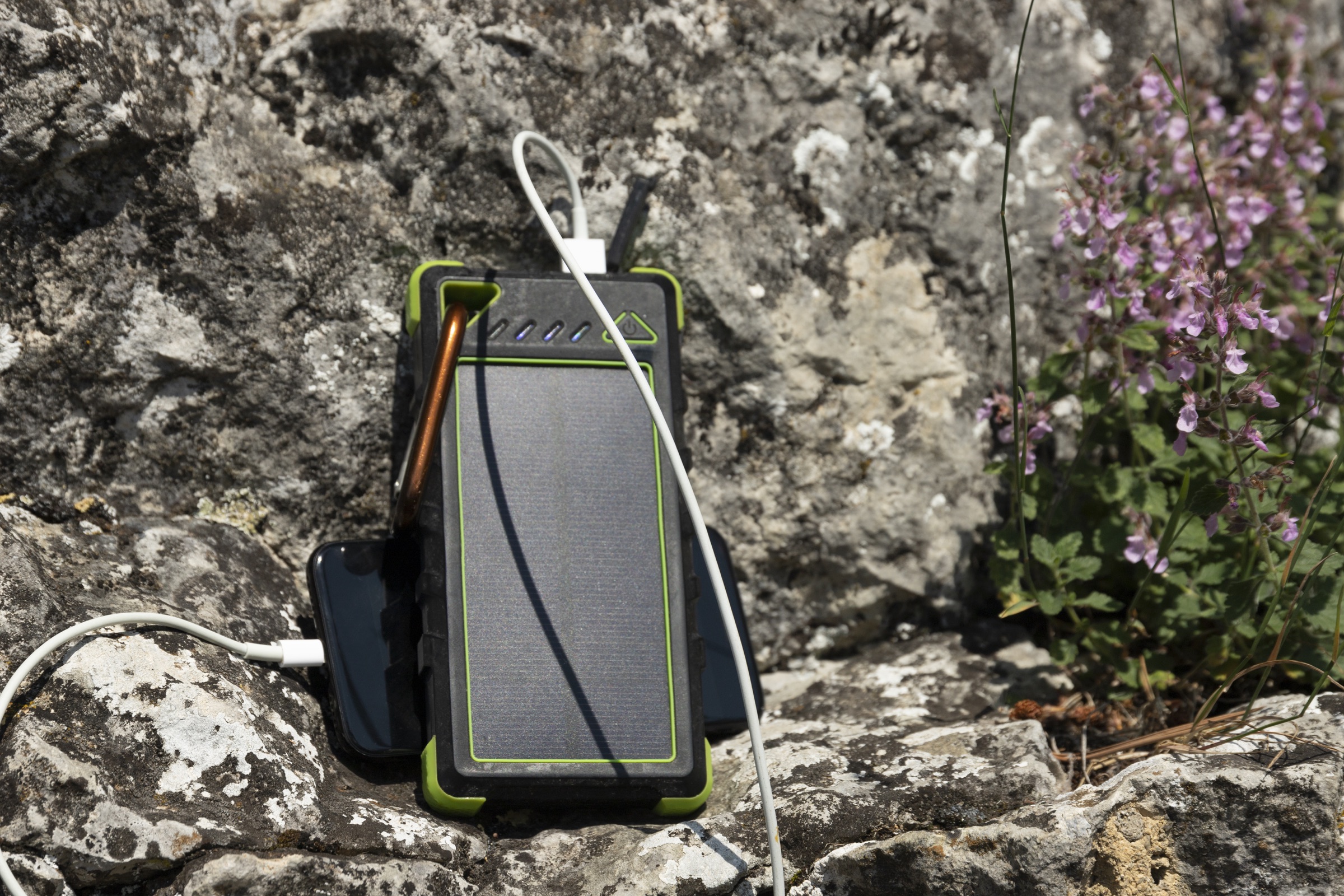 A compact solar power bank recharging a phone in direct sunlight