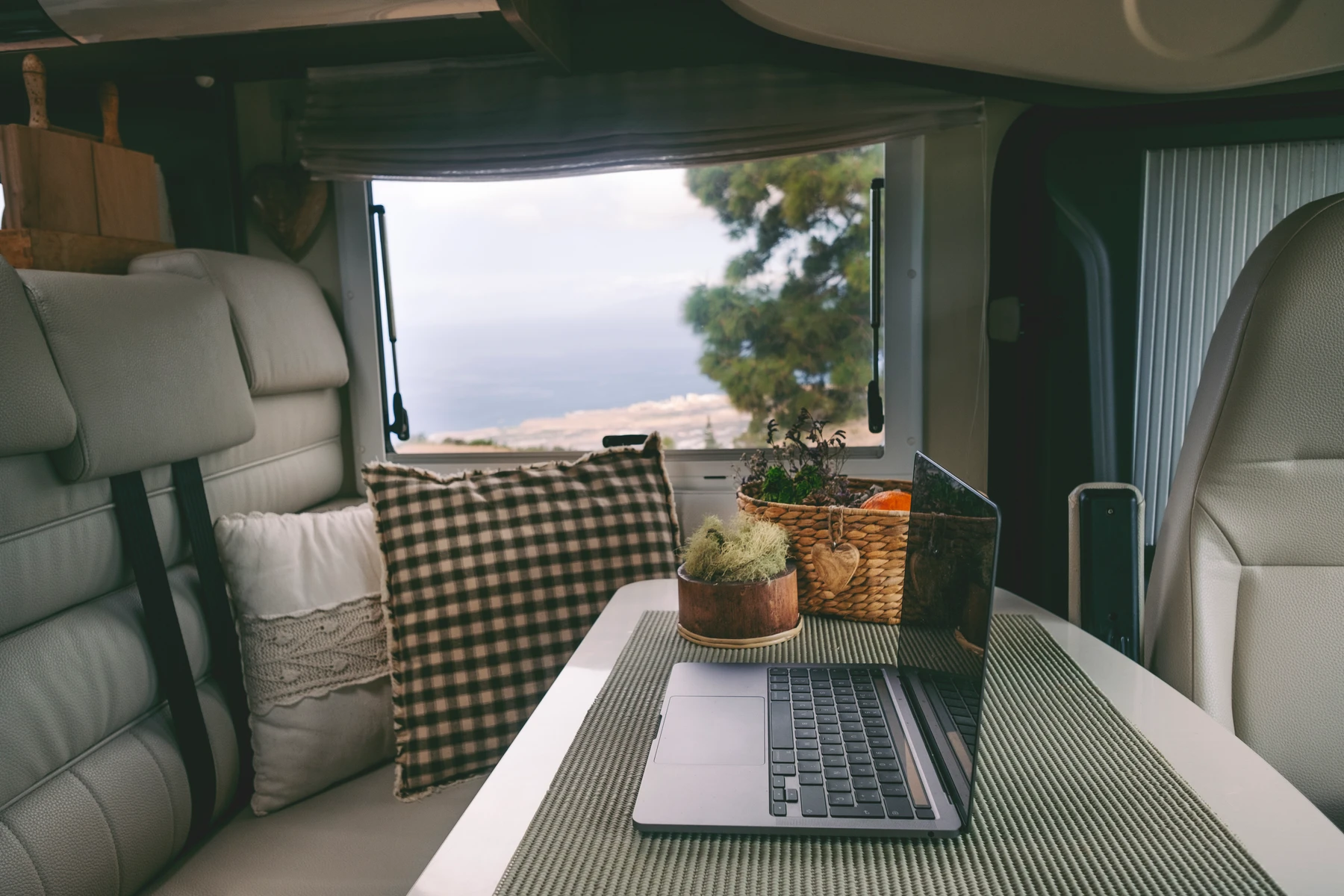 Laptop op tafel in een camper met uitzicht op zee: onderweg werken