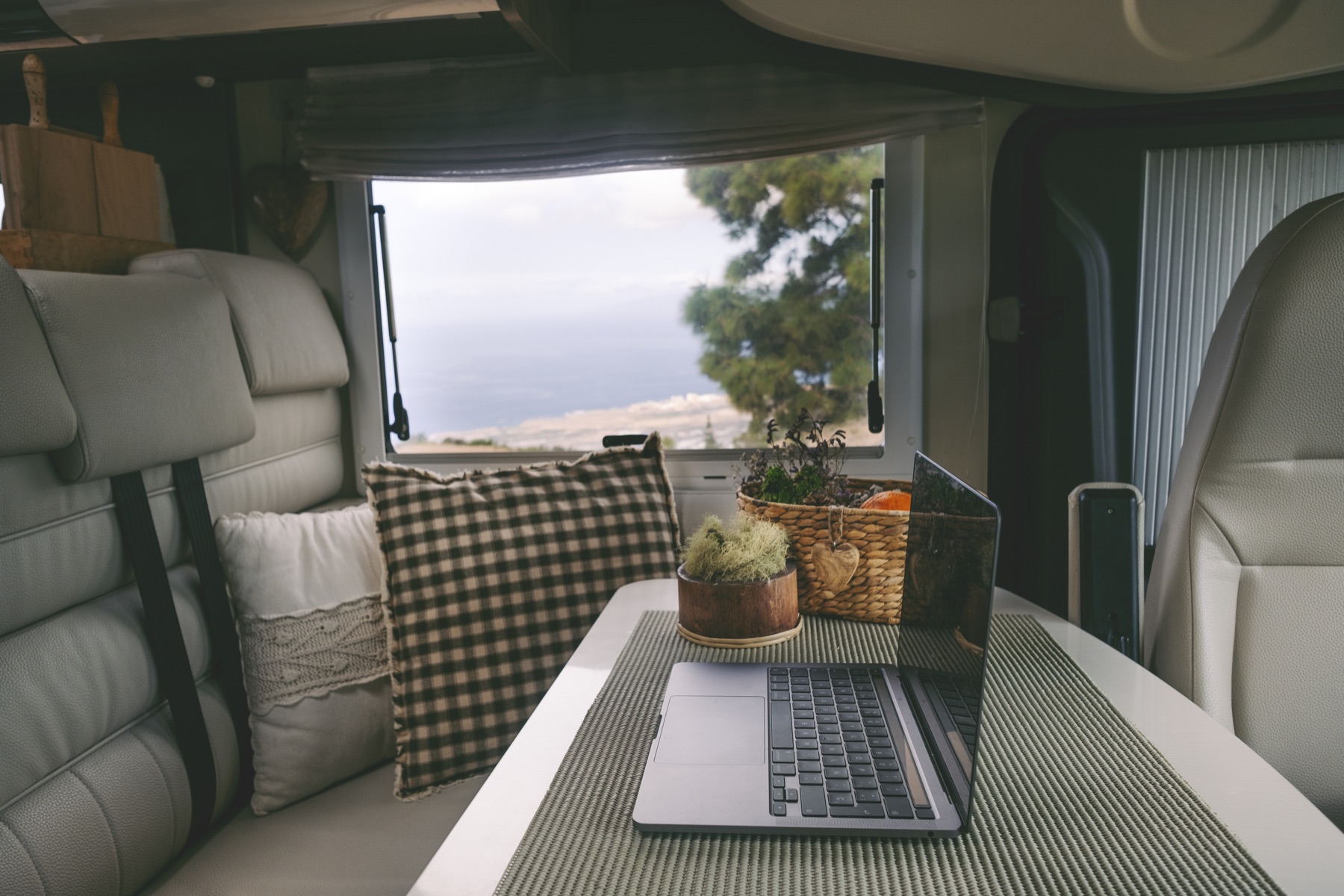 A laptop workspace inside a camper van overlooking nature