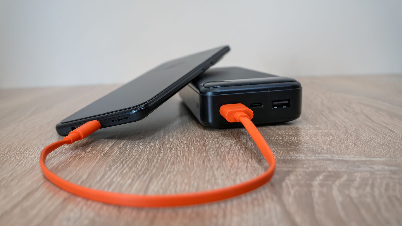 A smartphone connected to a compact power bank