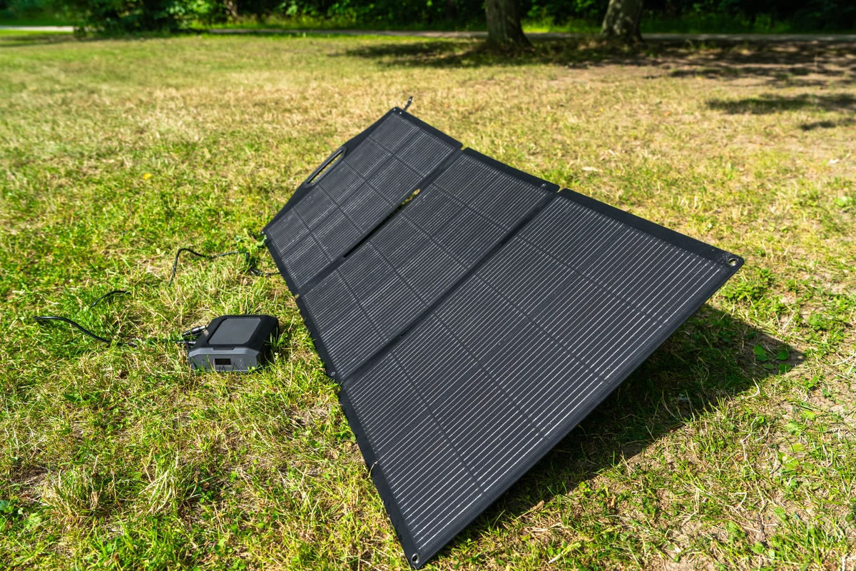 Foldable solar panel on grass connected to a portable power device