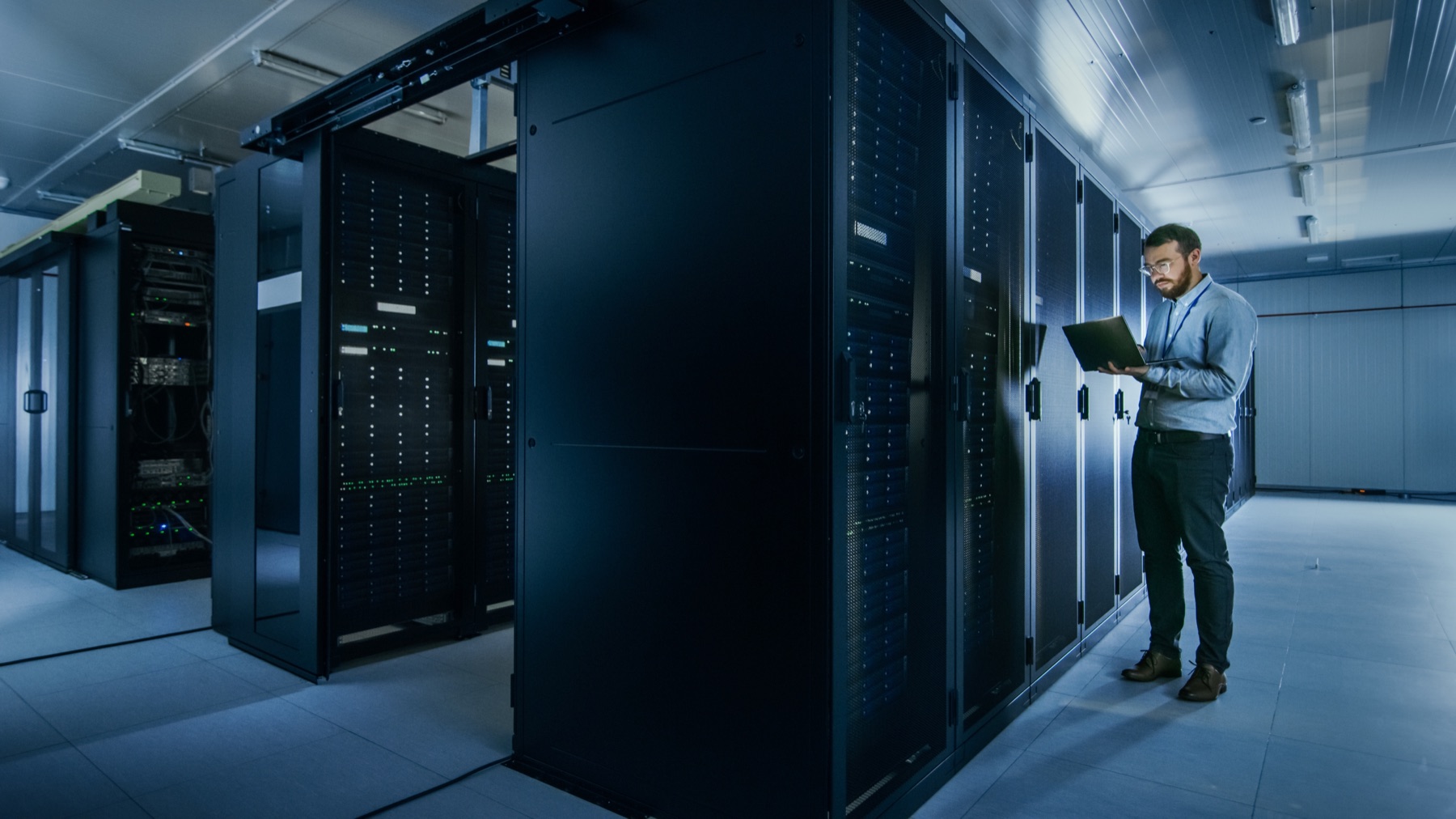 An IT specialist working beside server racks in a professional data room